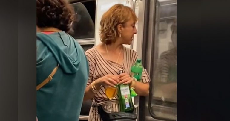Mujer viaja en el metro mientras toma whisky en una copa